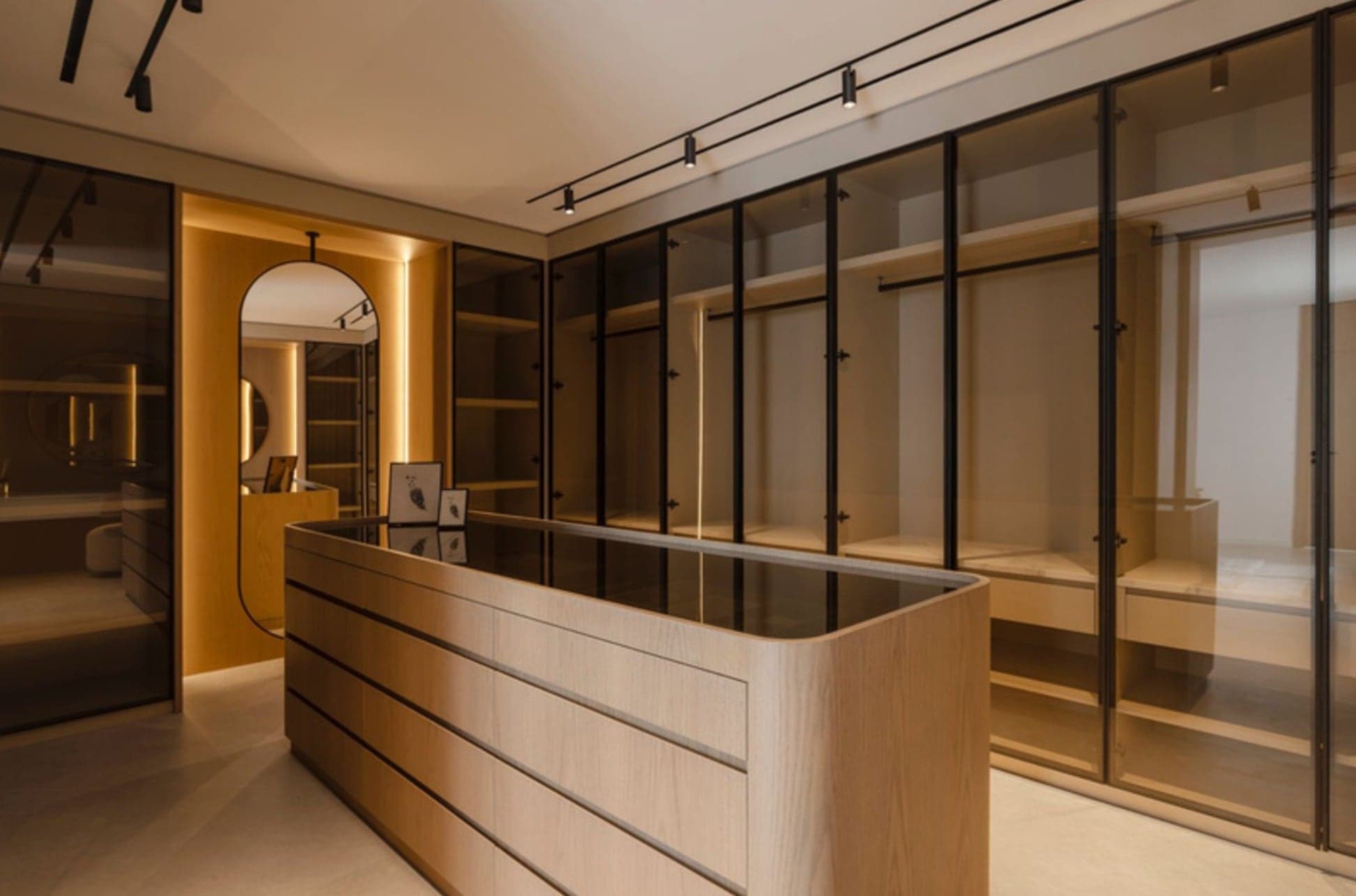 Walk-in wardrobe with framed glass-front cabinetry and a central island dresser