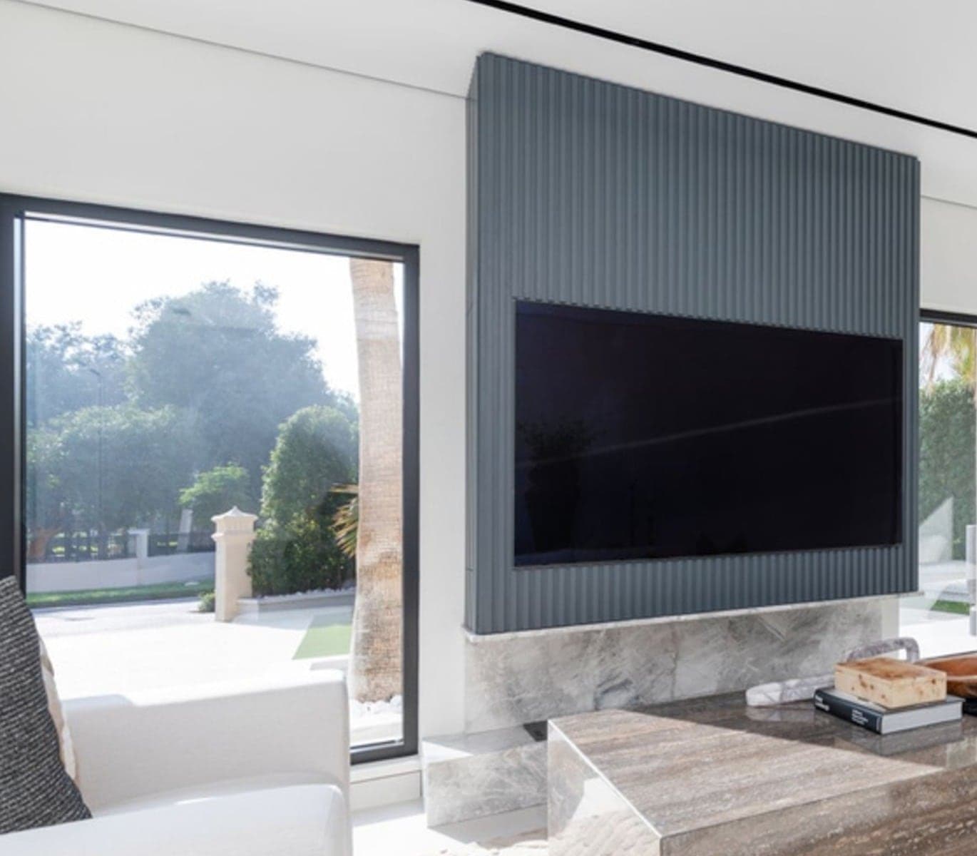 Media wall in fluted panelling with a stone base and integrated television